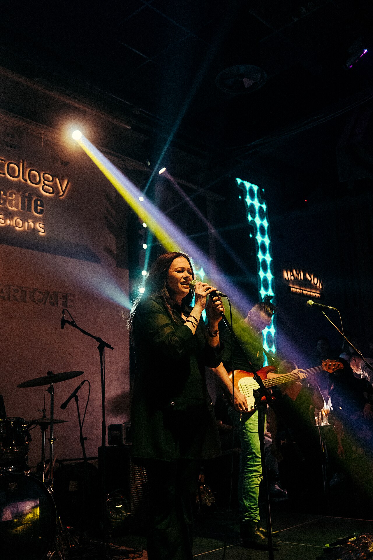 A singer performing passionately on stage, holding a microphone, with stage lights creating a dynamic atmosphere.